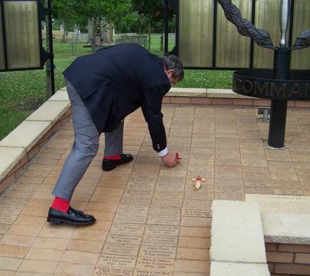 Ron 'Red Socks' Lain places a poppy on Bob Bartholemew's paver