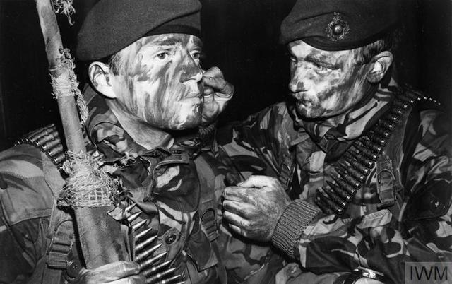 A Royal Marine of 3 Commando Brigade helps another to apply camouflage face paint in preparation for the San Carlos landings on