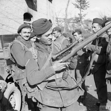 A Belgian commando inspects his rifle with sniper 'scope in a village at the foot of Mt Camino, 6 February 1944.