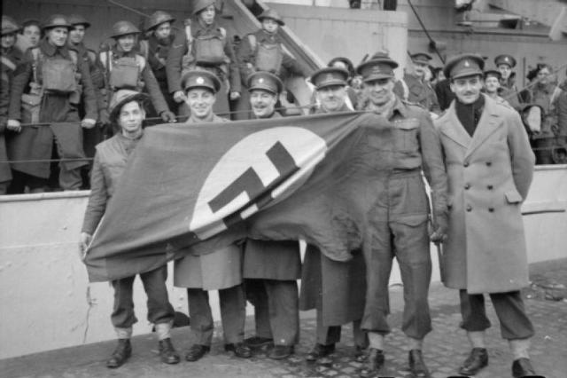 British officers with a captured Nazi flag after the raid.
